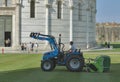 Worker mows the grass in front of the Baptistery in Pisa