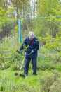 Worker mows grass and weeds with a lawn mower