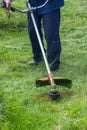 Worker mows grass and weeds with a lawn mower