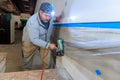 Worker nailing wooden trim moldings at room on a construction site