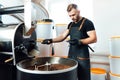 A worker near coffee roasting equipment will check time for testing the sample Royalty Free Stock Photo