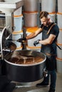 A worker near coffee roasting equipment will check time for testing the sample