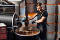 A worker near coffee roasting equipment will check time for testing the sample