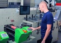 Worker next to the printing machine inputs the data by pressing the touch screen.