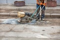 A worker rams fresh asphalt on a hole in an old road with a petrrol plate compactor