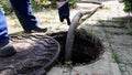 the worker opened the sewer hatch and inserted a hose for cleaning the septic tank. maintenance of communications in a Royalty Free Stock Photo