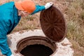 The worker opened the well hatch and looks inside. Troubleshooting, checking septic tanks