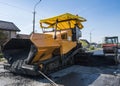 Worker operating asphalt paver machine during road construction and repairing works. A paver finisher, asphalt finisher