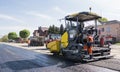 Worker operating asphalt paver machine during road construction and repairing works. A paver finisher, asphalt finisher