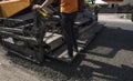 Worker operating asphalt paver machine during road construction and repairing works. A paver finisher, asphalt finisher