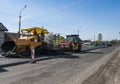 Worker operating asphalt paver machine during road construction and repairing works. A paver finisher, asphalt finisher