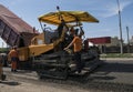 Worker operating asphalt paver machine during road construction and repairing works. A paver finisher, asphalt finisher