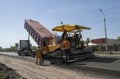 Worker operating asphalt paver machine during road construction and repairing works. A paver finisher, asphalt finisher