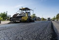 Worker operating asphalt paver machine during road construction and repairing works. A paver finisher, asphalt finisher