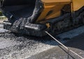 Worker operating asphalt paver machine during road construction and repairing works. A paver finisher, asphalt finisher Royalty Free Stock Photo