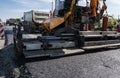 Worker operating asphalt paver machine during road construction and repairing works. A paver finisher, asphalt finisher