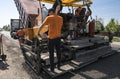 Worker operating asphalt paver machine during road construction and repairing works. A paver finisher, asphalt finisher