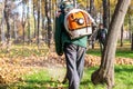 Worker operating heavy duty leaf blower in city park. Removing fallen leaves in autumn. Leaves swirling up. Foliage Royalty Free Stock Photo