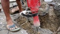 Worker operating a jackhammer to dig up a road for pipelining in Uttarakhand, India. Illustrating progress and development in