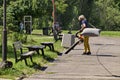 A worker operating a litter blower cleans a city park