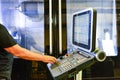 Worker, operator of the control panel of the program of operation of a high-precision CNC machining center, processing the manufac