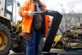 A worker in an orange vest uses a black mixture of bitumen during the laying and paving of new asphalt