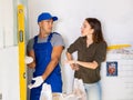 Worker using spirit level on wall with woman client Royalty Free Stock Photo