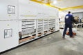 Worker in overalls carries the details along the rack of electrical equipment - manufacture of electrical equipment inside