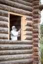 Worker in overalls and full face mask grinds a window opening in a freshly laid log house