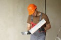 Worker in overalls and safety hard hat holds and prepares two spatulas for plastering concrete wall with putty using Royalty Free Stock Photo
