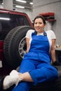 Worker in overalls sitting on tires in a garage