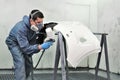 Worker painting a car bumper.