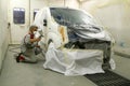 Worker painting a car on his garage