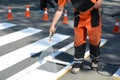 Worker is painting a pedestrian crosswalk. Technical road man worker painting and remarking pedestr Royalty Free Stock Photo