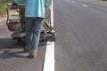 Worker painting traffic line with spraying eject machine.