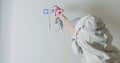 Worker painting the wall by airless spray gun with white color. Airless spray painting. Repair at home or office. Royalty Free Stock Photo
