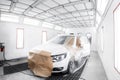 worker painting a white car in special garage, wearing costume and protective gear Royalty Free Stock Photo