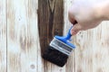 A worker painting a wooden wall. A man holding brush. A hand of worker painting wooden plank. A painter with paint brush Royalty Free Stock Photo