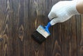 A worker painting a wooden wall. A man holding brush. A hand of worker painting wooden plank. A painter with paint brush Royalty Free Stock Photo