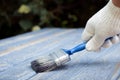 A worker painting a wooden wall. A man holding brush. A hand of worker painting wooden plank. A painter with paint brush Royalty Free Stock Photo