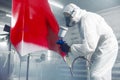 Worker paints car body part in workshop chamber using airbrush. Man using spray gun during auto painting. Royalty Free Stock Photo