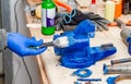 Worker paints a metal vise with blue paint. Stripping old paint