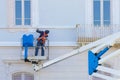 WORKER PAINTS THE WALL WHILE STANDING SAFELY ON A BASKET - Concept with aerial mechanical platform with protective basket Royalty Free Stock Photo