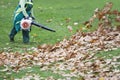 Worker in the park in autumn collects leaves