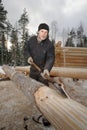 Worker peeled timber for log cabin construction using debarking