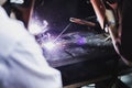 Worker perform electric metal welding in workshop class with a lots of spark. Focus on the workpiece.