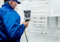 Worker performing powder coating of metal details at metallurgical factory Royalty Free Stock Photo