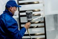 Worker performing powder coating of metal details at metallurgical factory Royalty Free Stock Photo