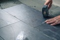 Worker placing ceramic floor tiles on adhesive surface