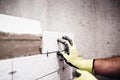 Worker placing small ceramic tiles with plastic spacer on bathroom walls